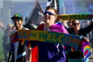 Dark Clouds member holding the 'All Are Welcome' Pride scarf (Photo: Daniel Mick)