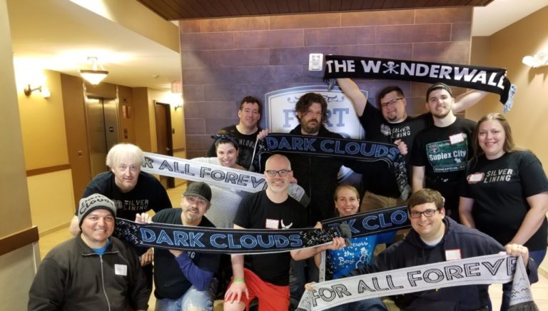 Several Dark Clouds volunteers standing in the lobby of an apartment building, holding up scarves.