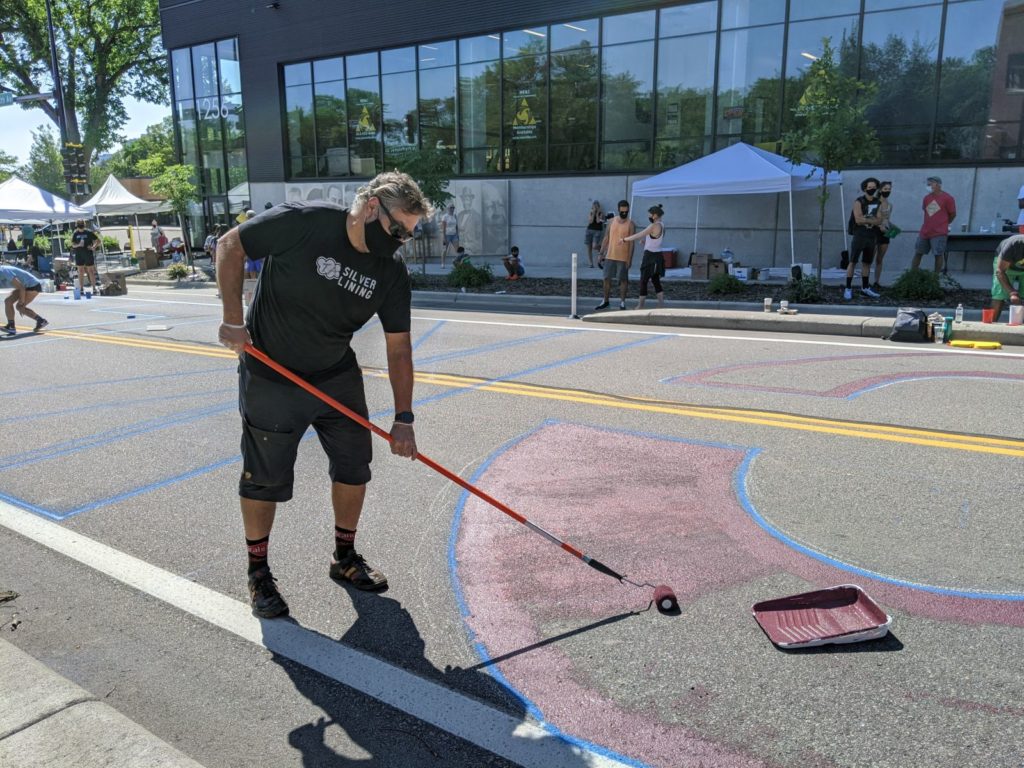 Dark Clouds volunteer Todd Anderson painting the BLM mural