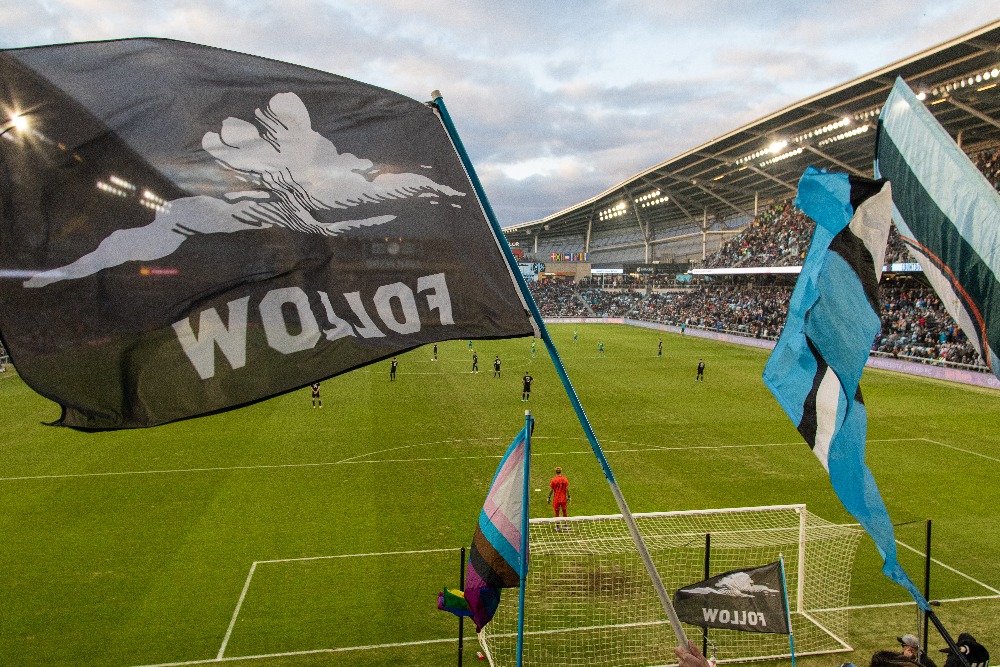 Several flags, including Dark clouds follow flag over field during Seattle and MNUFC game at Allianz field